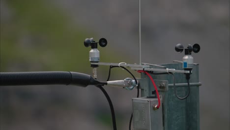 close-up view of two anemometers mounted on a metal support above a mountain railway pillar