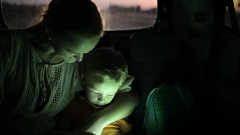 madre e hijo usando el touch pad en el coche por la noche
