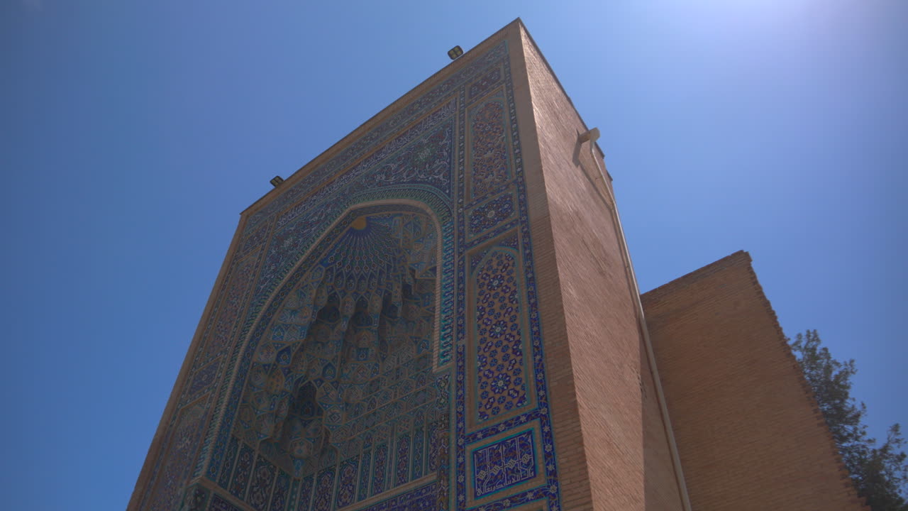 Portale ornato di madrasa nella piazza Registan a Samarcanda, Uzbekistan: architettura islamica con piastrelle a mosaico blu, storico punto di riferimento della Via della Seta, meta di viaggio in una giornata di sole, che rappresenta l'architettura del patrimonio asiatico.
