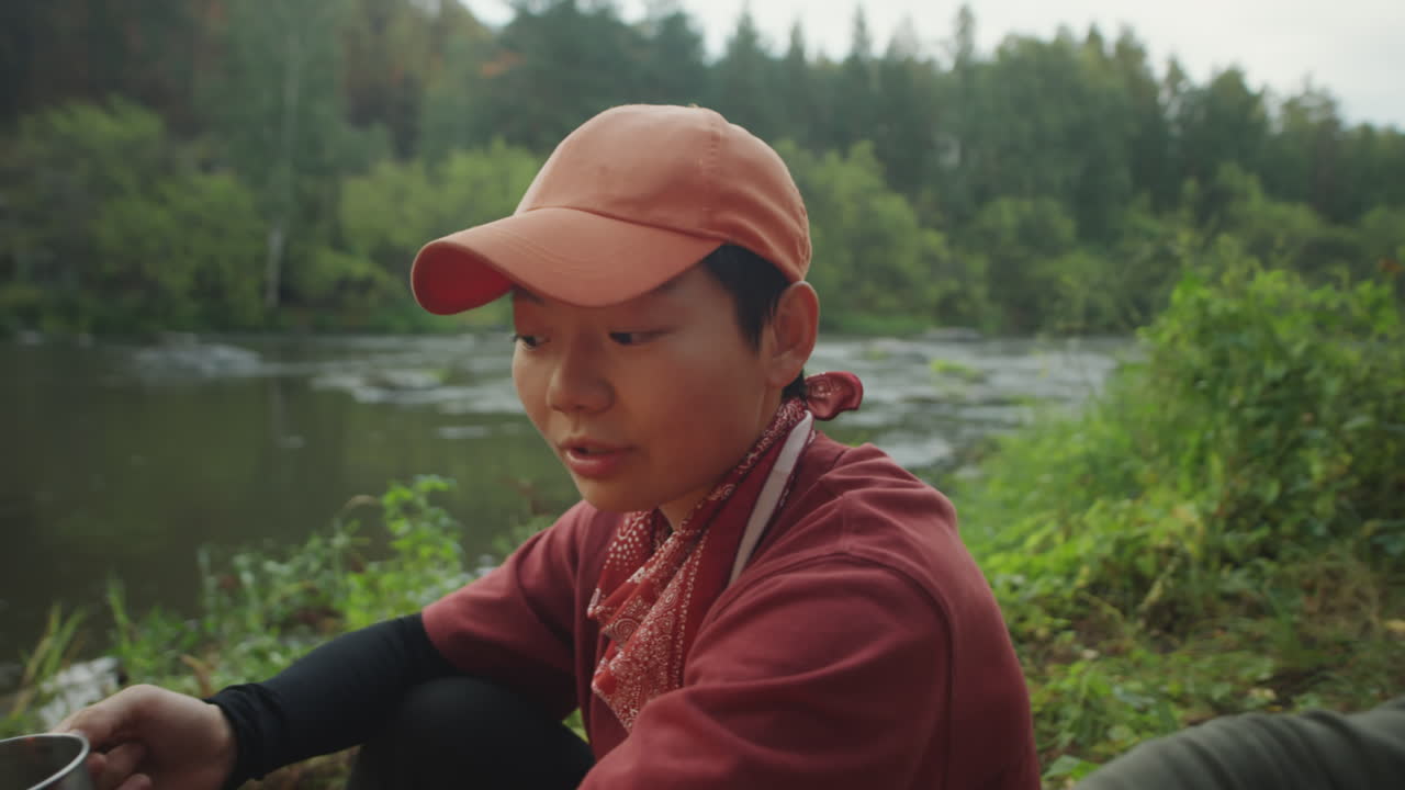 Female Tourists Warming by Campfire on Riverbank