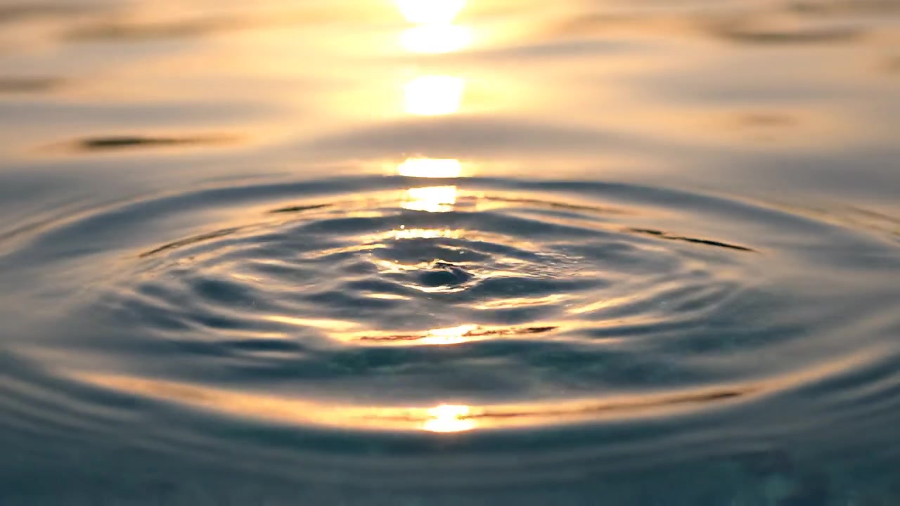 Schizzo d'acqua con increspature su superficie calma al tramonto dorato
