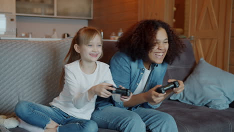 two girls playing video games on a couch