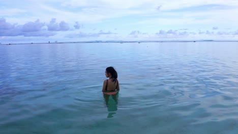 a woman traveler swims on crystal clear beach of gunung payung in bali, indonesia