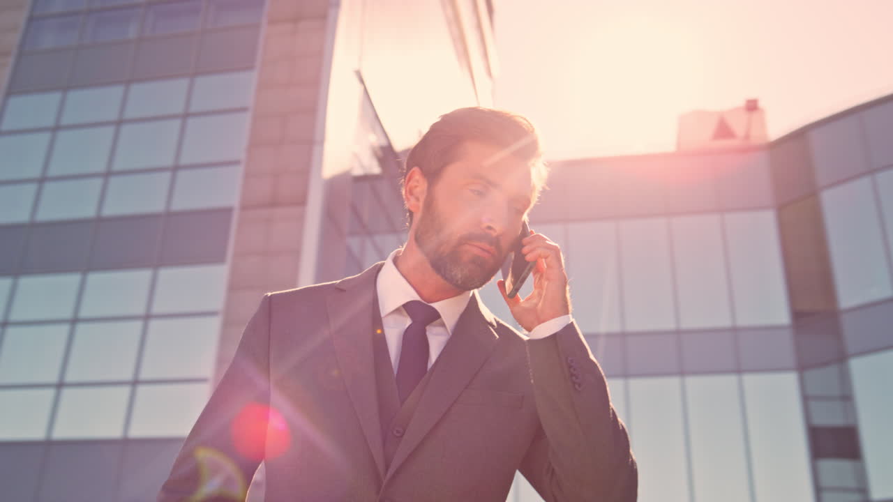 проблемный бизнесмен звонит по мобильному на солнечной улице.