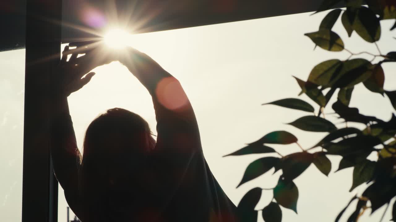 задний вид пожилой женщины, простирающейся в пламени солнца