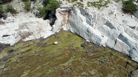 A-Bird's-Eye-Vista-of-Aliki's-Enchanting-Ancient-Marble-Quarry,-adorned-with-Turquoise-Waters-and-Glistening-White-Marble,-in-Thassos,-Greece