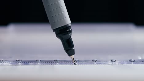 close-up of a pen drawing a line with a ruler