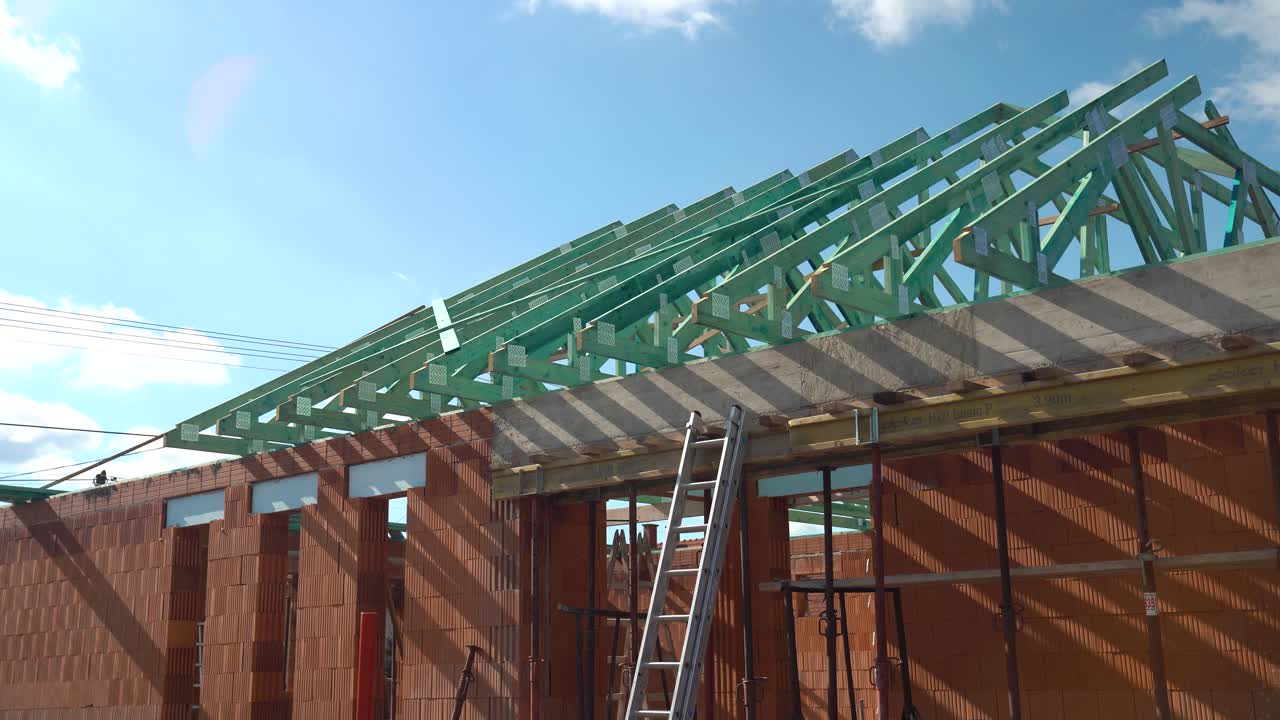 Exterior of unfinished brick house with green timber trusses being installed