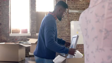diverse colleagues packing boxes with documents and office items in creative office in slow motion