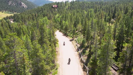 two motorcycle riders drive towards the camera with an aerial view dolly backwards in the mountains