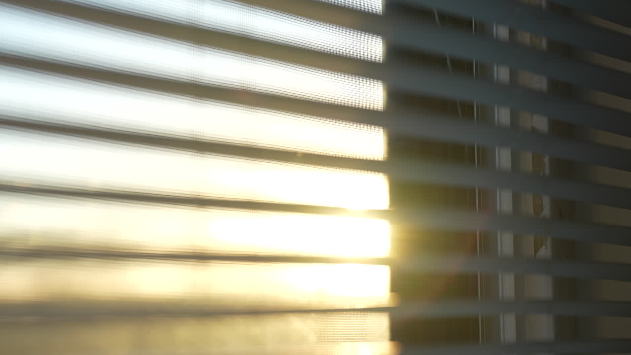 Golden hour sunset through apartment window blinds