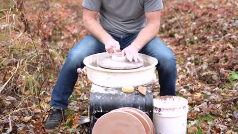 a potter is working outdoors on his pottery wheel