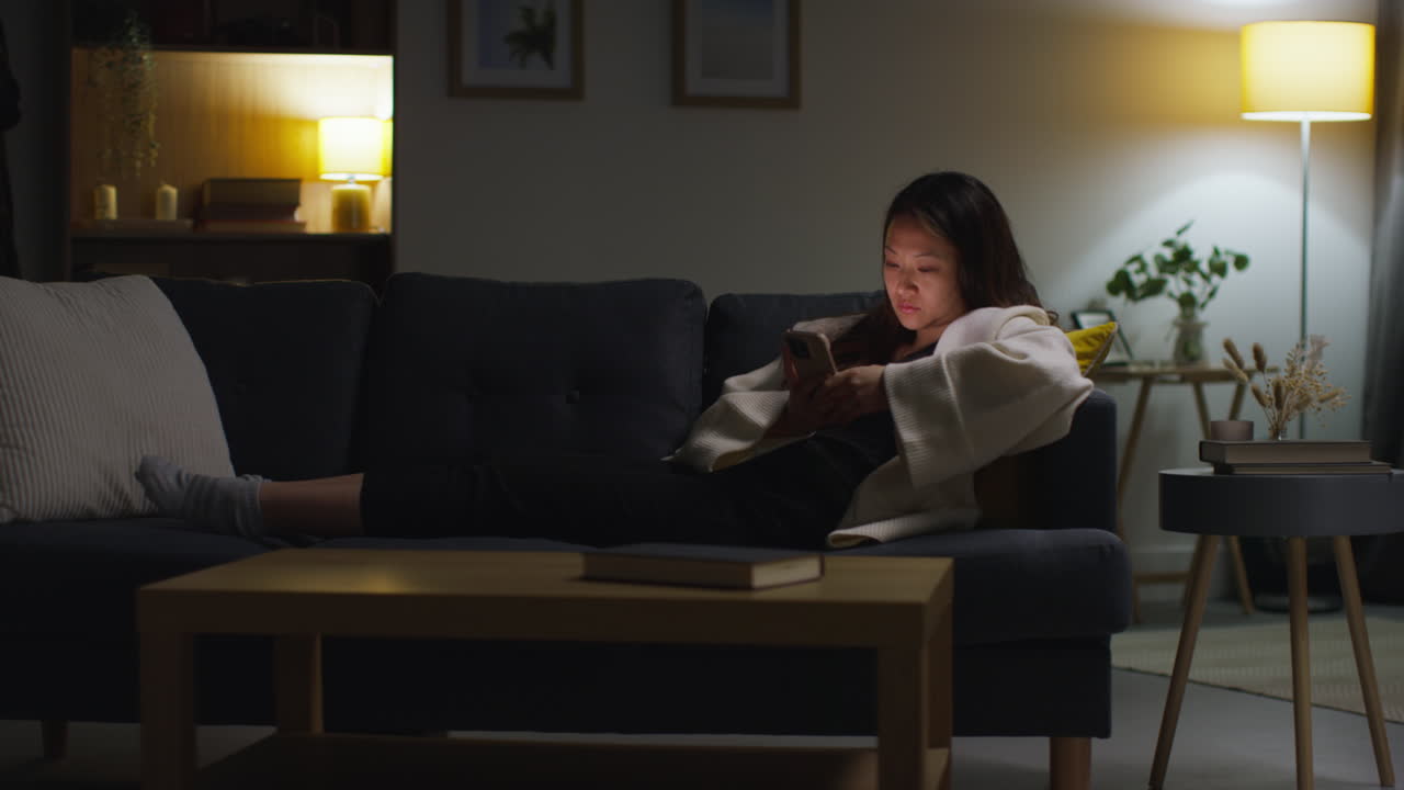 mujer que pasa la noche en casa acostada en el sofá con el teléfono móvil navegando por internet o las redes sociales 14