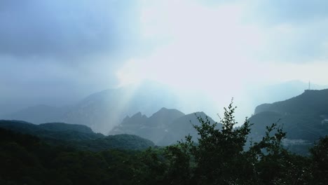 wide vista of yun tai shan geopark, henan province - green misty mountains, light streaks piercing through mist, and far peaks evoking a chinese ink painting