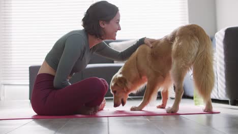 Mujer-Caucásica-Manteniéndose-En-Forma-Y-Sentada-En-Una-Estera-De-Yoga-Con-Un-Perro