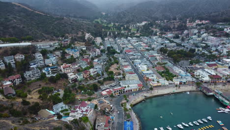 Antena-Sobre-Villas-En-Las-Laderas-Y-Aguas-Azul-Turquesa-De-La-Playa-De-La-Ciudad-De-Avalon,-Santa-Catalina,-California