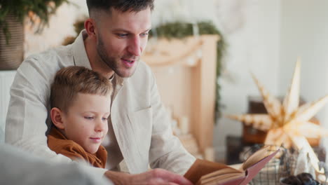 primo piano di un padre che legge un libro a suo figlio