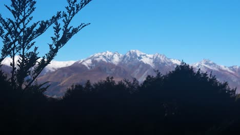 panorama view of mountain range with snowy peak against blue sky in summer - glacier burn hike in new zealand - wide shot