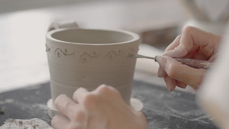 woman hands during painting on ceramic plates. potter workshop of making handcraft clay dishes. artist creates a beautiful pattern on earthenware in a pottery workshop. close-up slow motion