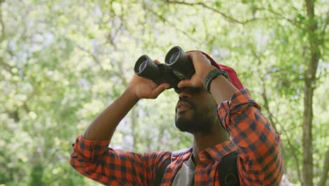 hombre afroamericano feliz usando binoculares en el parque, cámara lenta