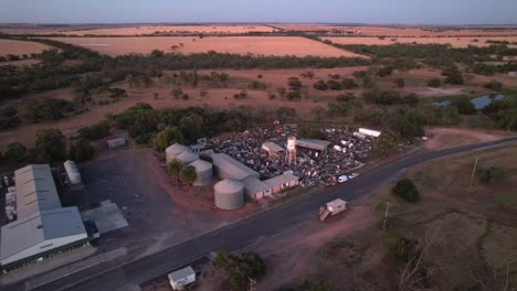 Aerial-dawn-rural-scrap-yard-surrounded-by-fields-Sea-Lake,-Australia