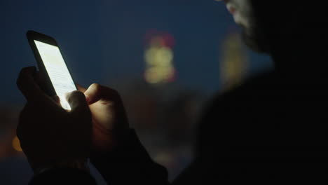 person messaging on smartphone at night in city