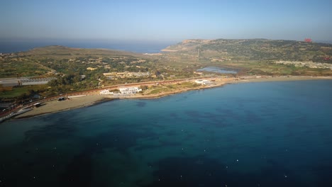 Drohnenaufnahme,-Die-An-Einem-Wunderschönen-Morgen-In-Malta-Aus-Der-Ferne-Den-Strand-Von-Mellieha-Umkreist