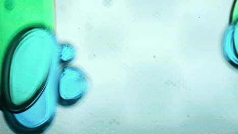 blue and green liquid bubbles moving slowly inside a vertical lava lamp. the abstract and fluid motion creates a calming and visually engaging effect