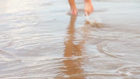 womans feet walking on the wet sand along the tide