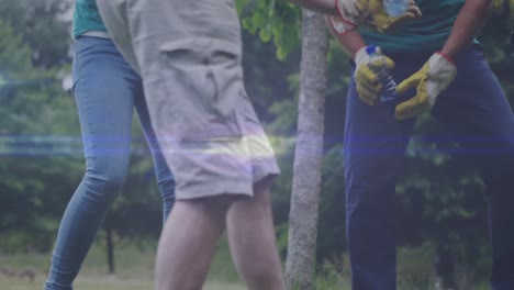 Video-of-lights-over-diverse-volunteer-group-picking-up-rubbish-in-countryside