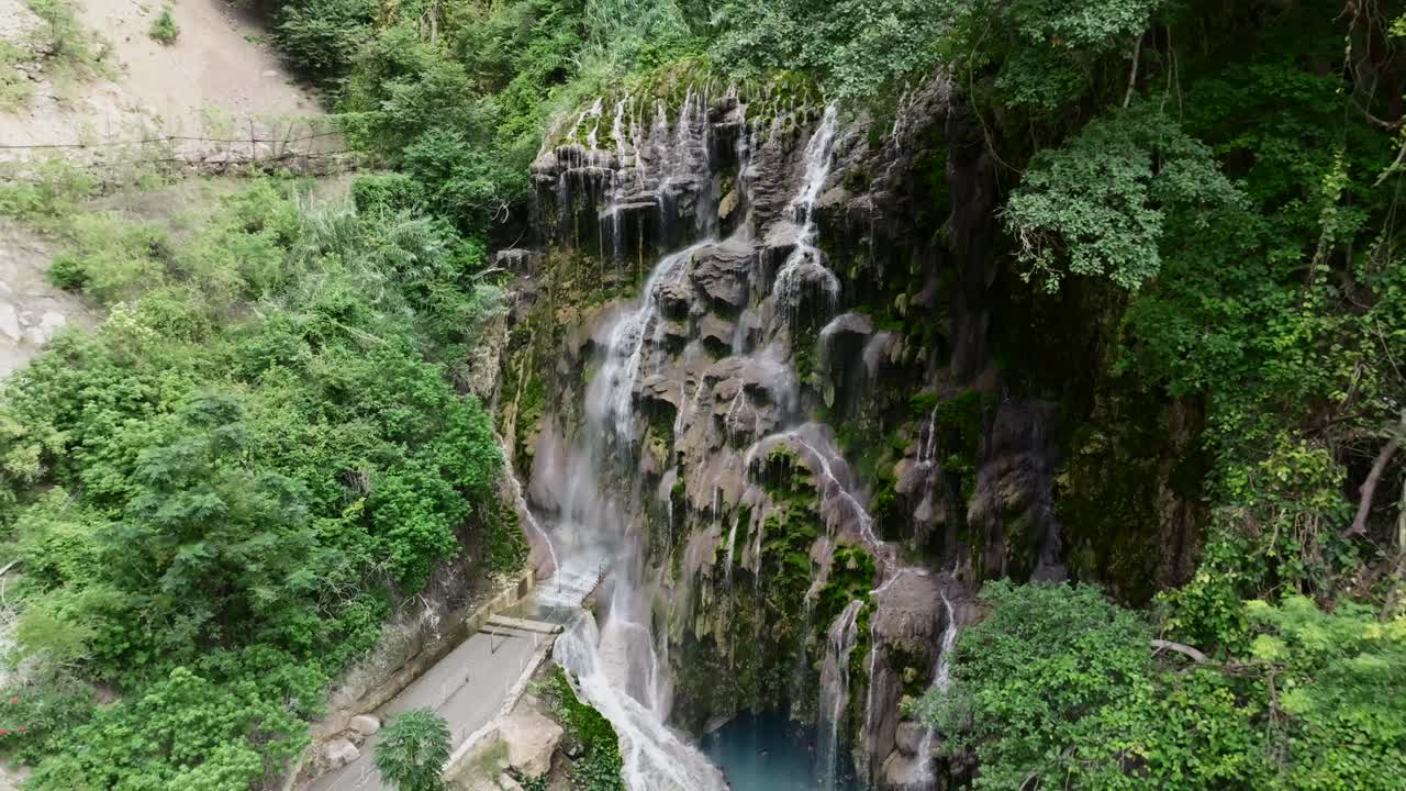 Backwards drone aerial reveals the La Gloria waterfall and spa resort at Grutas Tolantongo, Mexico