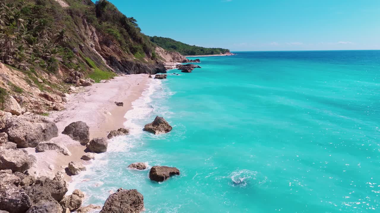 Picturesque hidden sandy beach with bright clear turquoise colored Caribbean Sea. Coastline of Barahona, USA. Aerial Birds Eye shot
