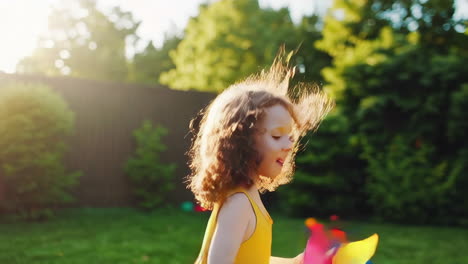 little girl playing with a pinwheel in a sunny backyard