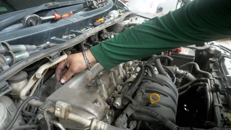 A closer look at a mechanic unscrewing some parts of the car&#039;s engine to repair it in a machine shop in Bangkok, Thailand