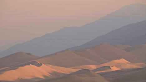 telephoto landscape of massive sand dunes with mountain range behind