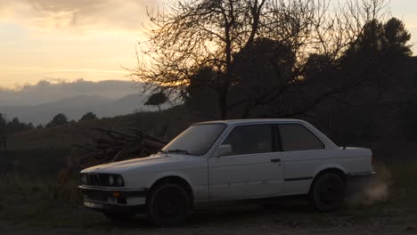 males arrives in white car at sunrise pulling up on dirt road