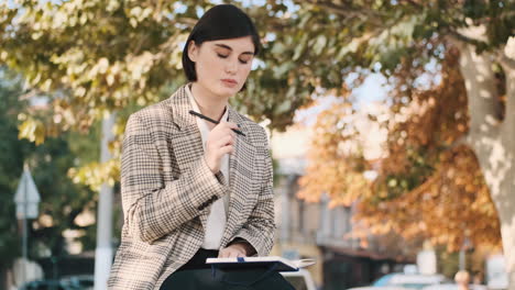 female entrepreneur drawing up business plan for a month in notepad while resting outdoor.