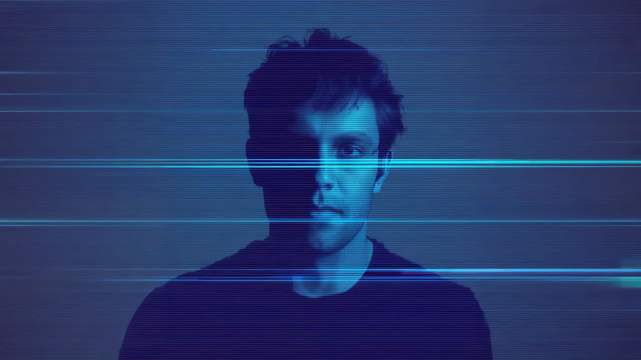 Responding male standing in studio, smiling as cyan scanlines moving across frame, wearing dark tee