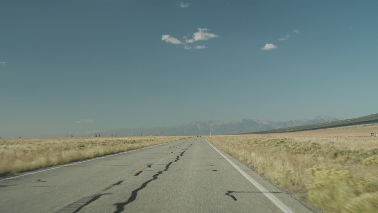 Open road under blue sky with mountains in the distance