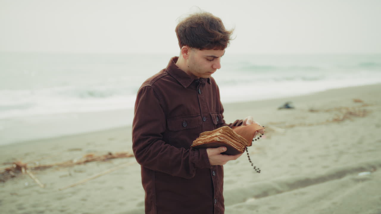 Man Reading The Bible And Flipping The Pages On The Shore