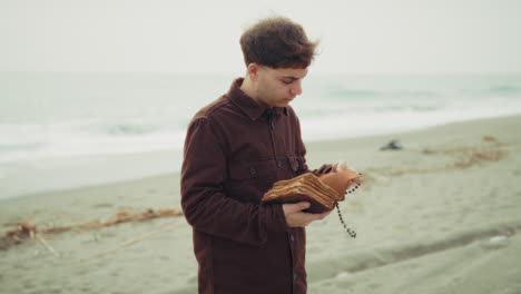 man reading the bible and flipping the pages on the shore