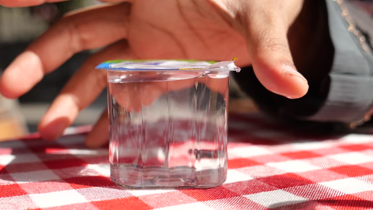 una persona sosteniendo un vaso de agua en un café al aire libre