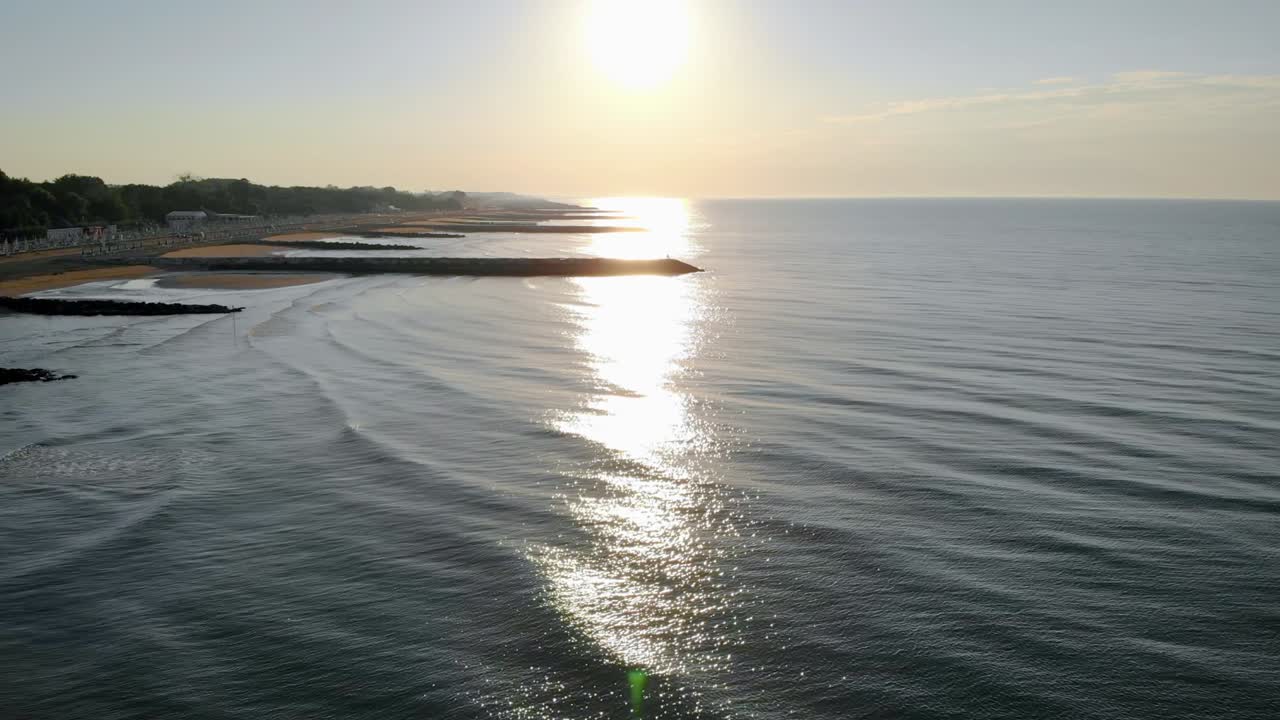 Volo aereo sopra il mare Adriatico che riflette il tramonto sulla spiaggia di Caorle, una località costiera di Venezia.