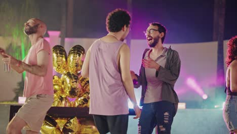 friends enjoy a lively outdoor night party with colorful lighting and golden balloons