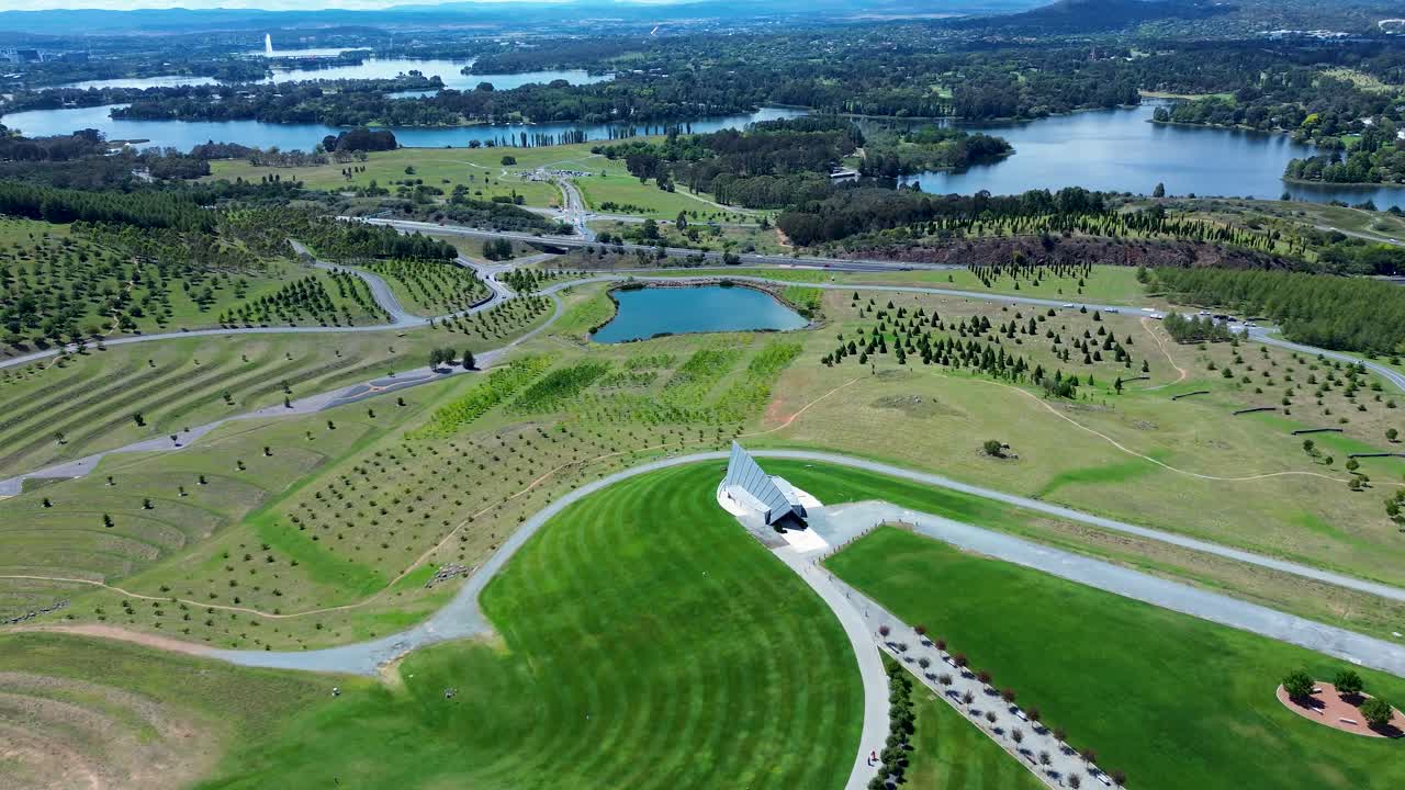 Drone aerial landscape of pavilion building and lake dam in grassy valley of National Arboretum Canberra botanical gardens Lake Burley Griffin ACT Australia travel tourism architecture