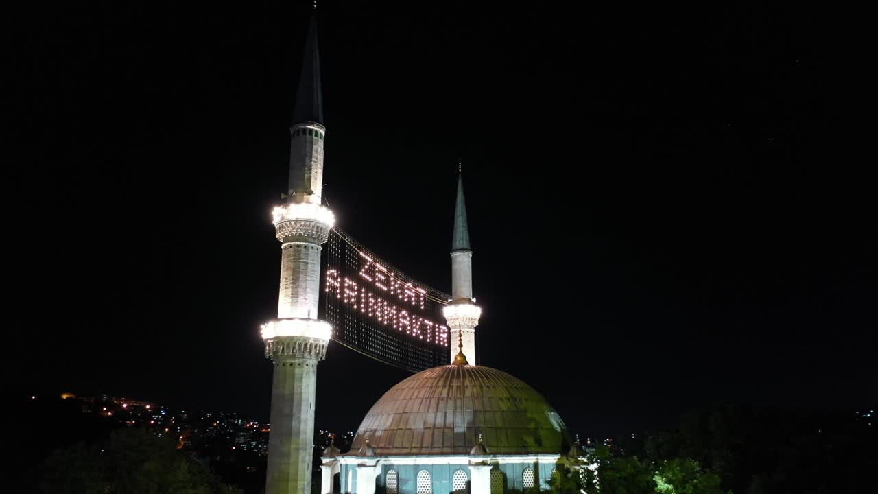 vista aérea nocturna de la mezquita de eyup sultan. dice "la limosna es purificada".