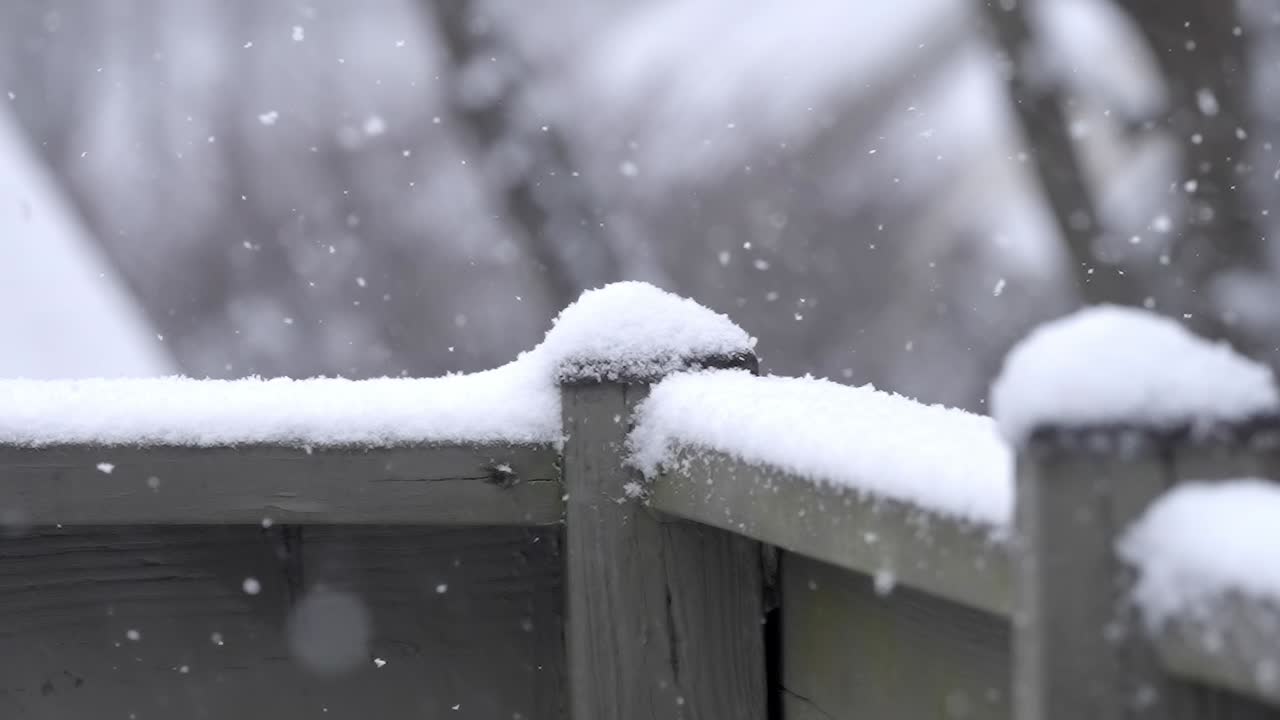 Snowfall on a railing, cold winter day, slow motion shot of small snowflakes falling outside on a wooden railing, static shot, copy space