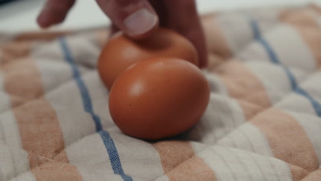 hand placing two organic brown eggs on a checkered towel