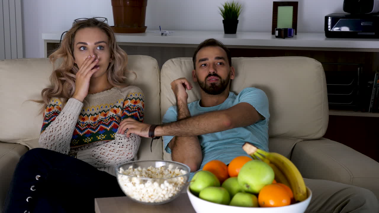 Coppia che guarda la TV con degli snack
