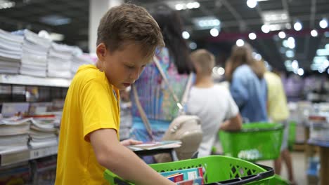 young boy in shop. boy choosing notebook in the store